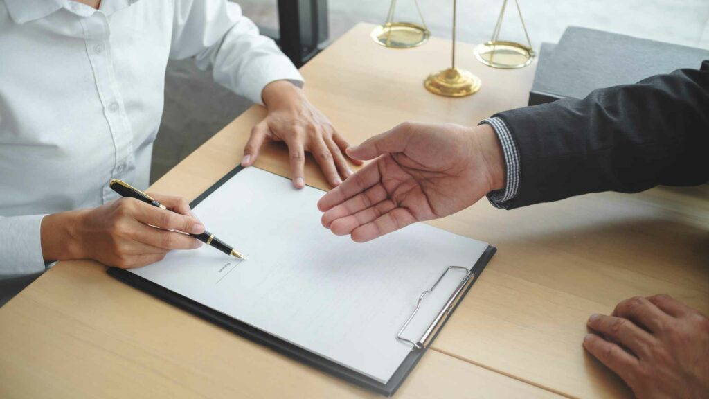 dos personas firmando un contrato de trabajo y estrechando la mano